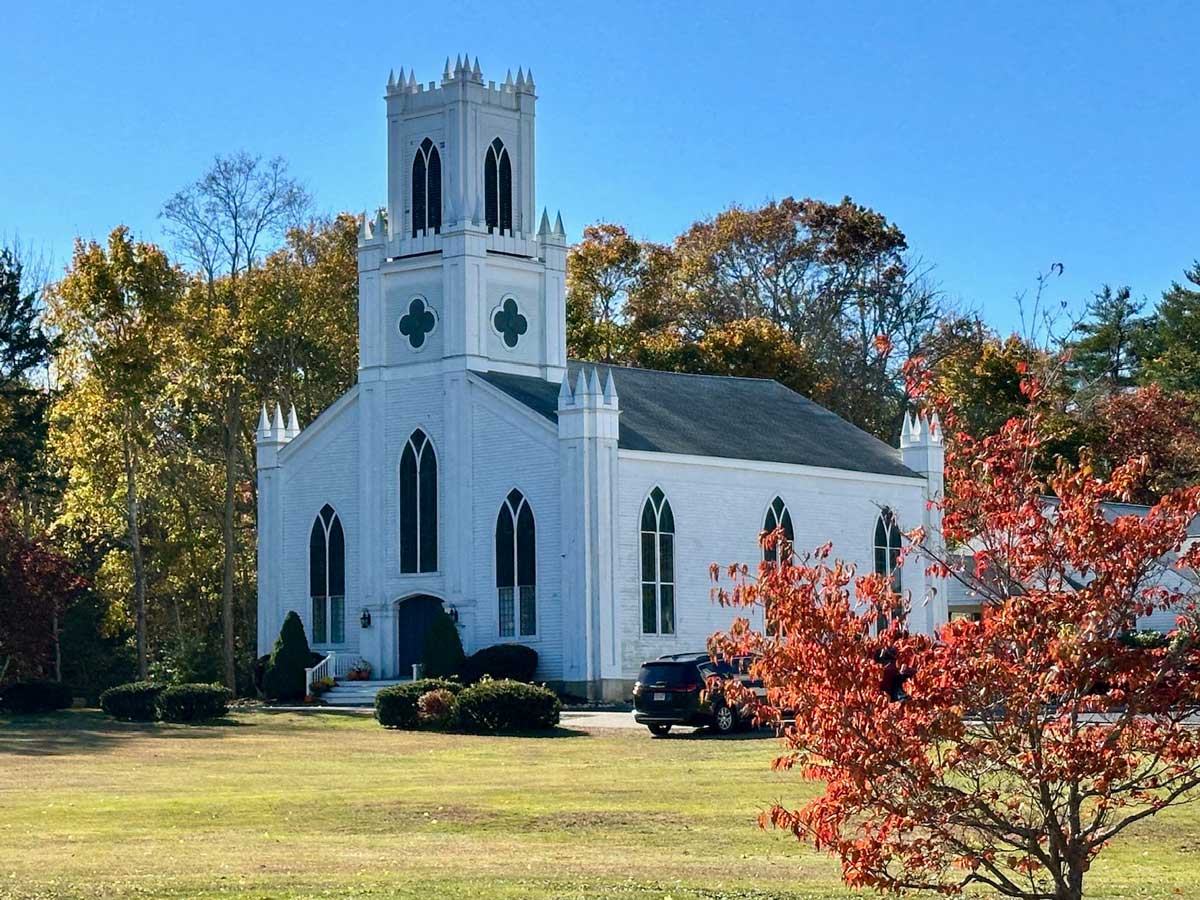 White church surrounded by trees in the fall.